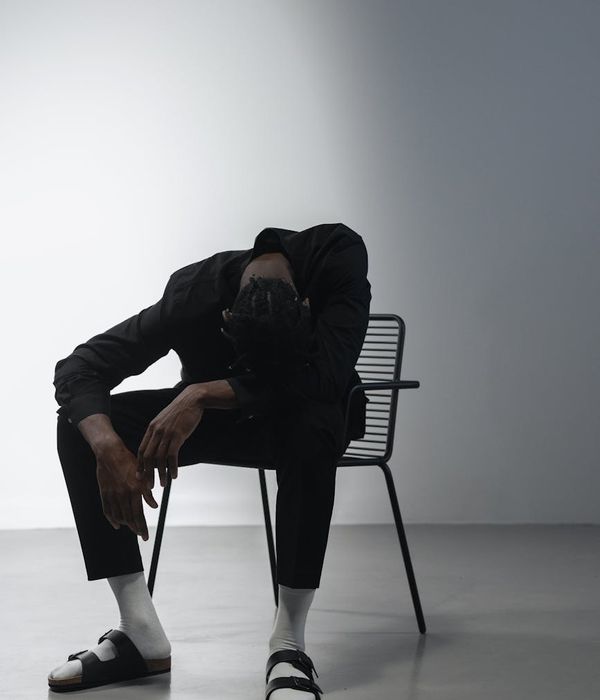 Person sitting in a meditative posture in a minimalist dark room with amber light.